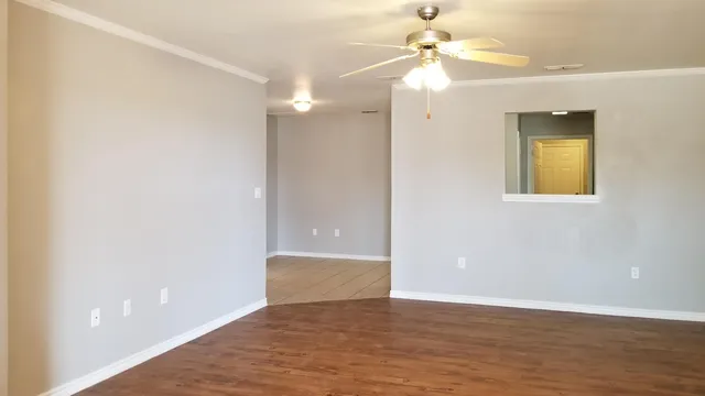 a view of an empty room with window and wooden floor
