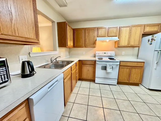 a kitchen with a sink a stove top oven cabinets and a window