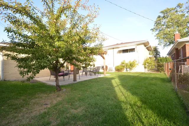 a view of a backyard with table and chairs and potted plants and large trees