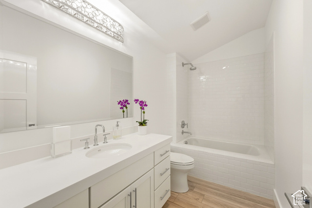 369 East Overlook Loop Kamas, UT 84036 - Photo 30 of 64 Vanity with a single basin sink and brushed nickel faucet, large wall-mounted mirror, decorative light fixture, white subway tile shower surround, and wood-finish flooring