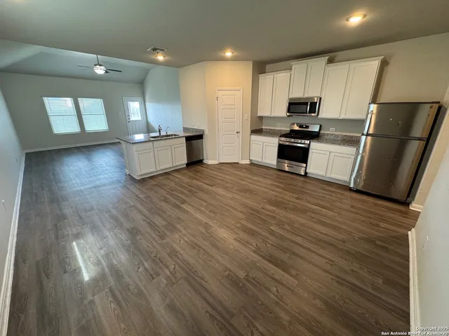 a kitchen with stainless steel appliances granite countertop a refrigerator sink and white cabinets