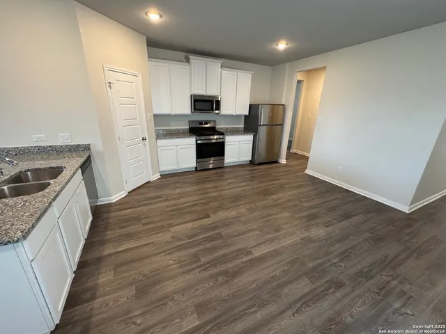 a kitchen with granite countertop a refrigerator stove and sink