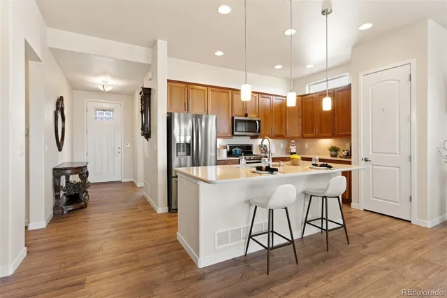 a kitchen with stainless steel appliances granite countertop a refrigerator oven a sink a stove and island with wooden floor