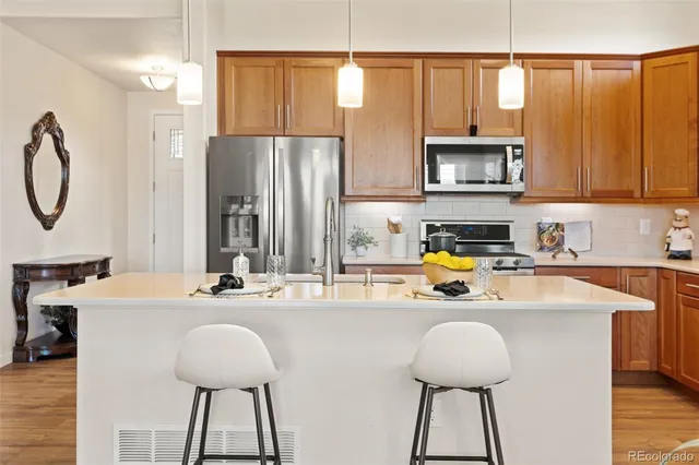 a kitchen with stainless steel appliances a sink a stove a refrigerator cabinets and a dining table with wooden floor