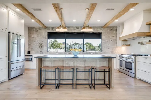 a kitchen with stainless steel appliances granite countertop a sink a stove and a wooden floors