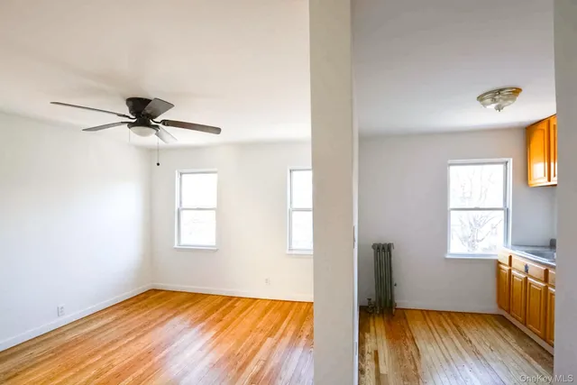 a view of empty room with wooden floor and fan