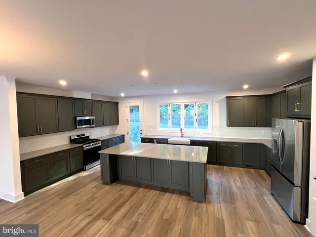 a large kitchen with stainless steel appliances a large counter top a stove and a refrigerator