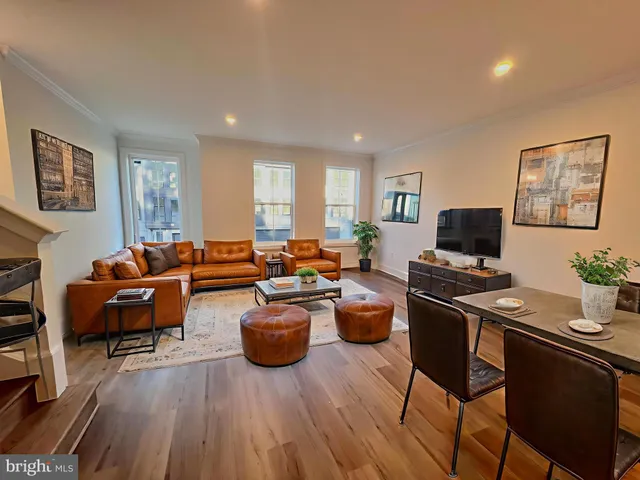 a living room with furniture a flat screen tv and a refrigerator