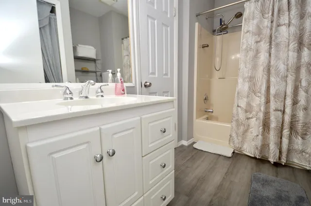 a spacious bathroom with a double vanity sink a mirror a bathtub and shower