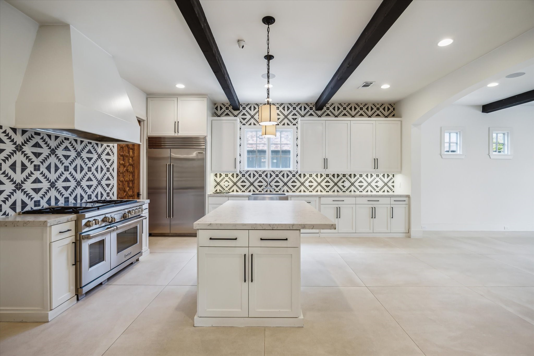 3214 Westheimer Road Houston, TX 77098 - Photo 19 of 39 Dual pendant lights and a black-and-white cement tile backsplash add a modern aesthetic to this beautifully appointed kitchen. High-end appliances and custom finishes complete the look.