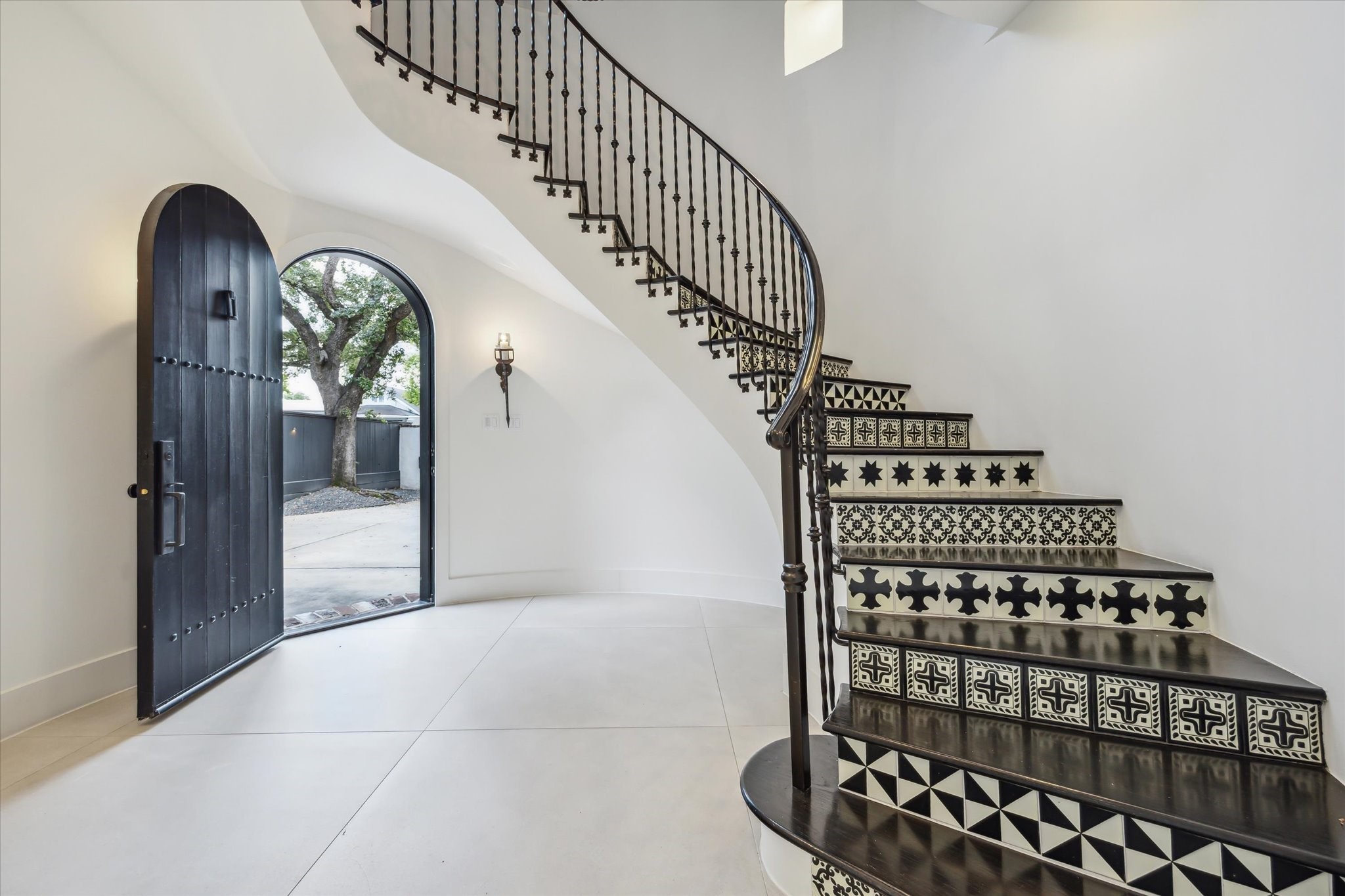 3214 Westheimer Road Houston, TX 77098 - Photo 5 of 39 The dramatic foyer boasts travertine tile flooring, a curved staircase with custom cement tile risers, and an antique chandelier. Recessed LED lighting enhances the space, creating a luminous and elegant entryway. This grand design leaves a lasting impression on all who enter.