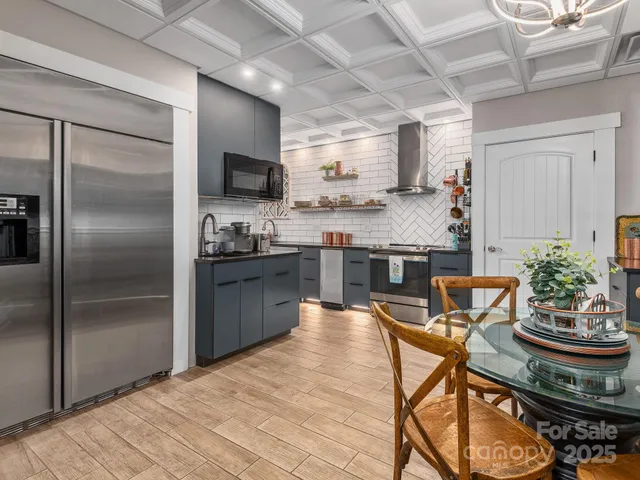 a kitchen with stainless steel appliances granite countertop a stove a refrigerator a sink a dining table and chairs with wooden floor