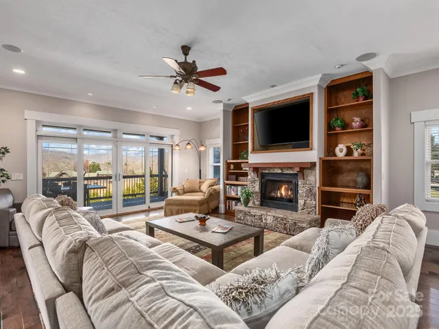 a living room with furniture a fireplace a flat screen tv and a large window