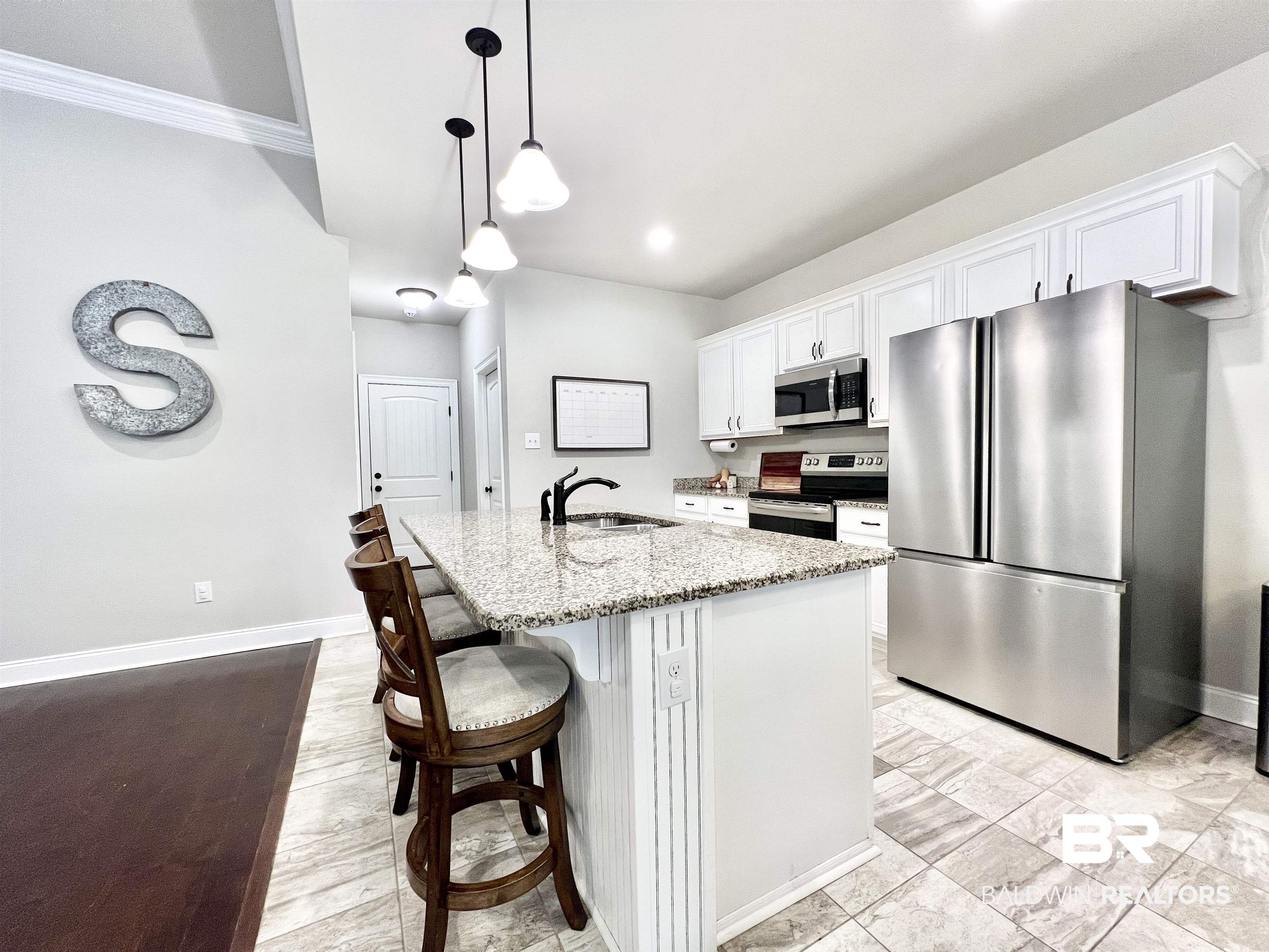 32290 Calder Court Daphne, AL 36527 - Photo 20 of 59 Kitchen with white cabinets, a center island with sink, light stone countertops, decorative light fixtures, and stainless steel appliances