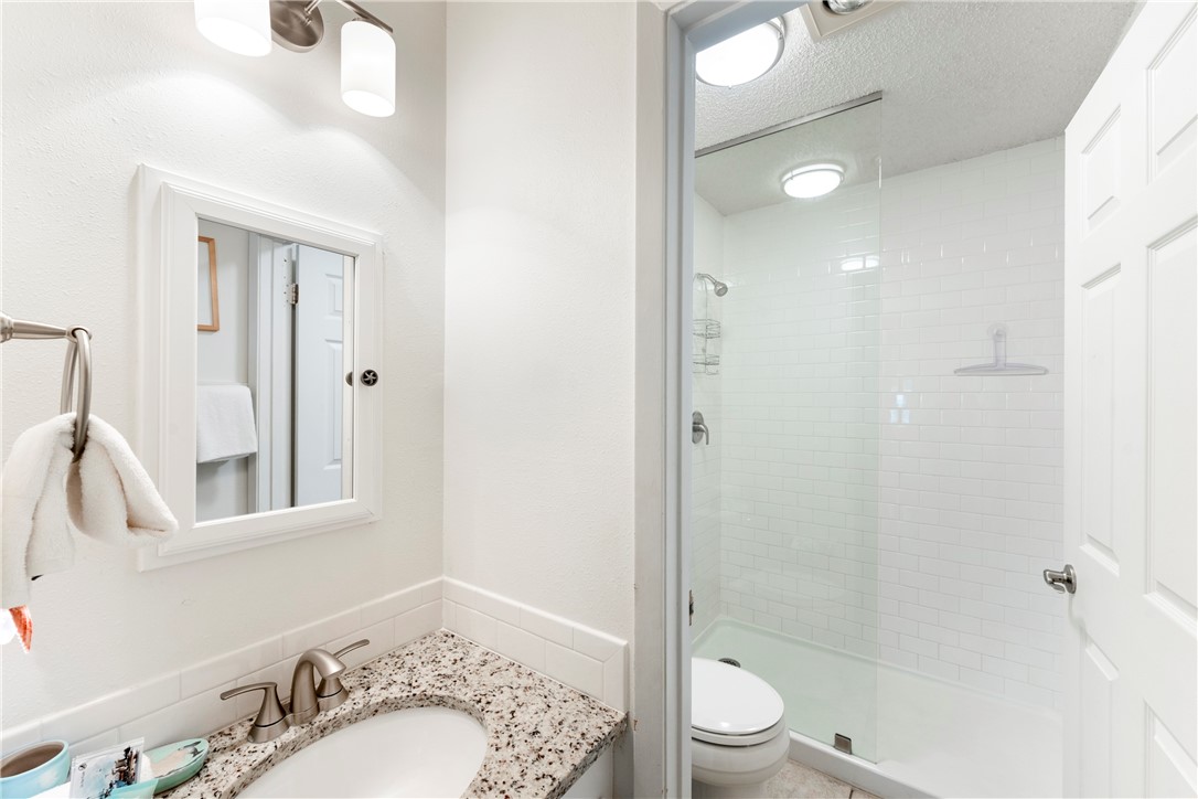 622 Beach Access Road, Unit 229 Port Aransas, TX 78373 - Photo 11 of 24 a bathroom with a granite countertop sink toilet a shower and a mirror