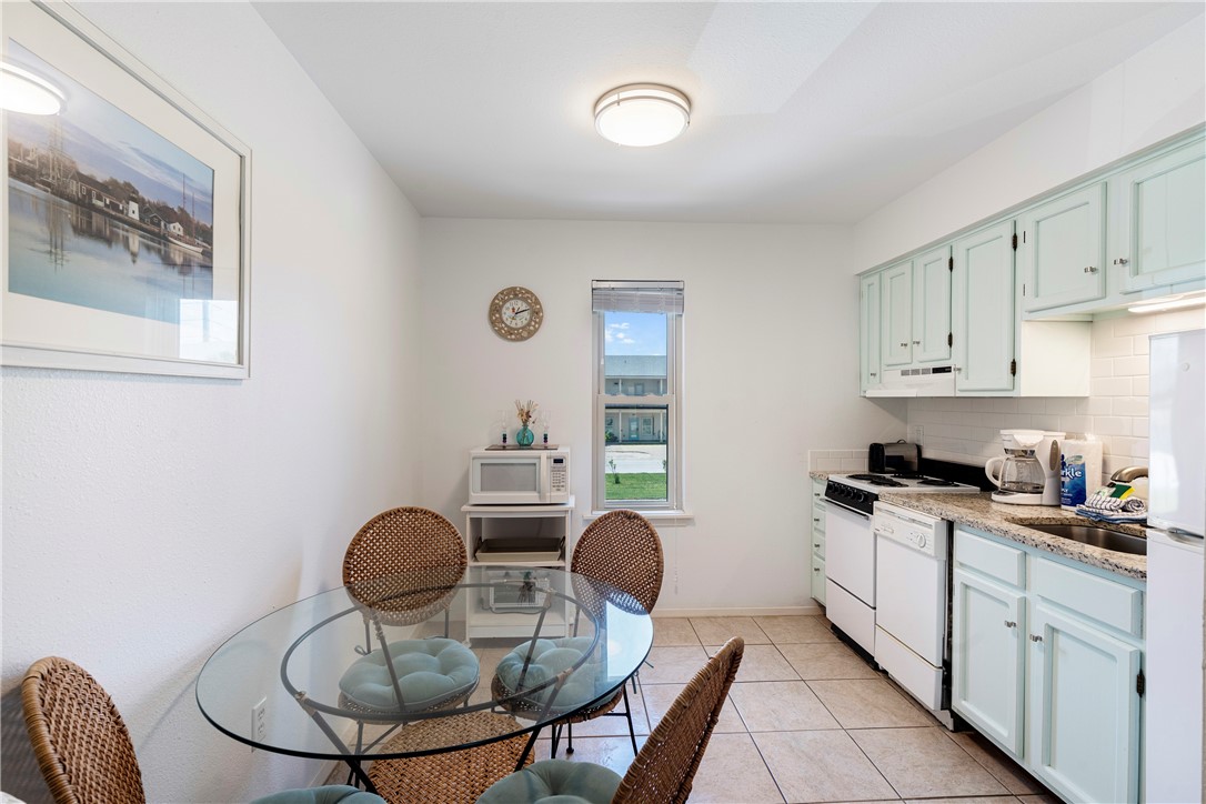 622 Beach Access Road, Unit 229 Port Aransas, TX 78373 - Photo 10 of 24 a kitchen with granite countertop cabinets a stove a dining table and chairs
