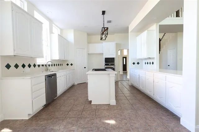 a kitchen with stainless steel appliances a white cabinets and window