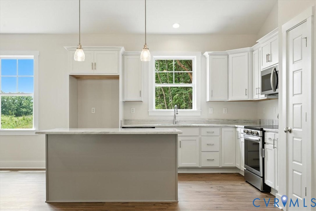 3898 Horseshoe Road Appomattox, VA 24522 - Photo 15 of 32 a kitchen with stainless steel appliances granite countertop a stove a sink and white cabinets with wooden floor