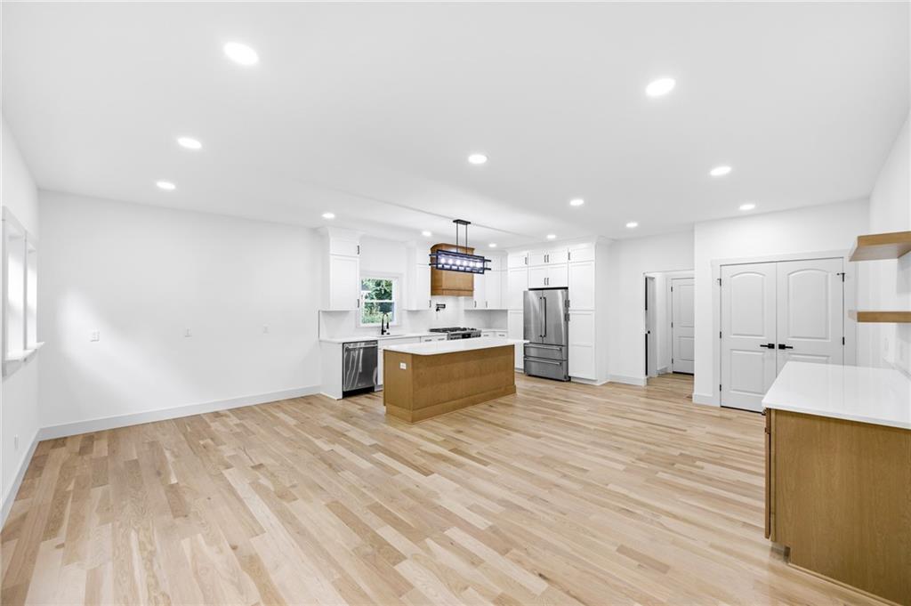 1749 Patriots Way Northwest Kennesaw, GA 30152 - Photo 18 of 54 a large room with kitchen island a sink dishwasher stove and white cabinets with wooden floor