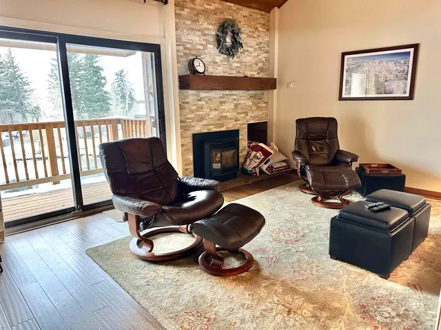 a living room with furniture a fireplace and a floor to ceiling window