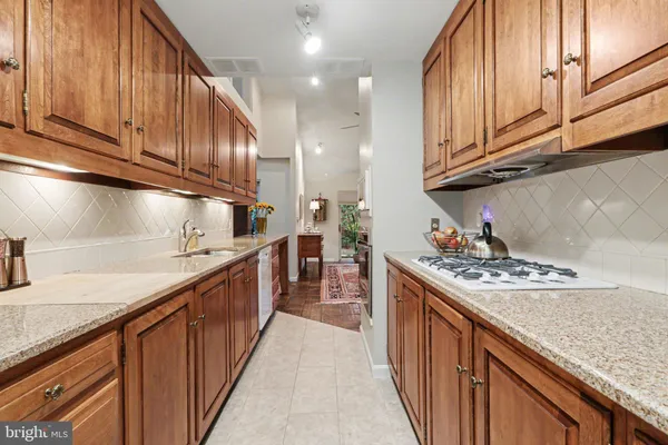 a kitchen with stainless steel appliances granite countertop a stove a sink dishwasher and cabinets with wooden floor