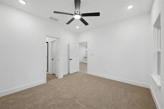 an empty room with windows and ceiling fan