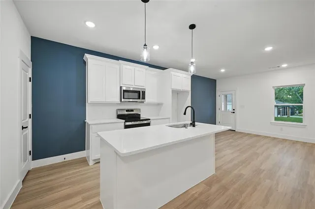 a kitchen with stainless steel appliances a stove top oven a sink a refrigerator a center island and cabinets