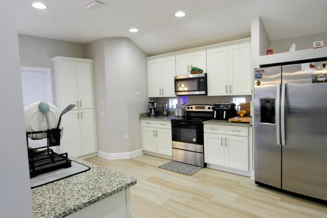 a kitchen with granite countertop a refrigerator stove and microwave