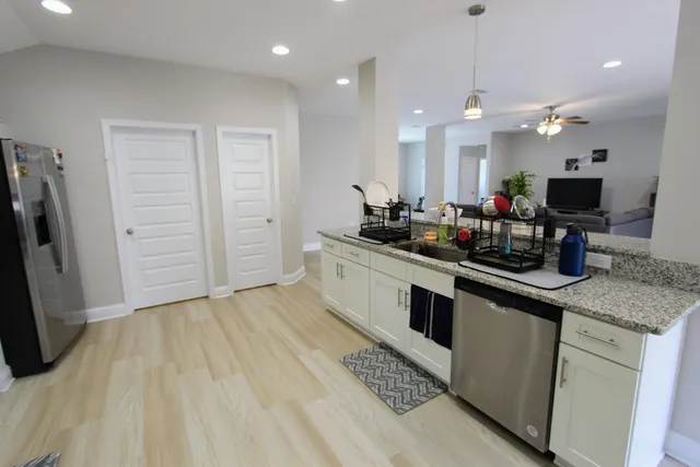 a kitchen with stainless steel appliances kitchen island granite countertop a sink cabinets and wooden floor