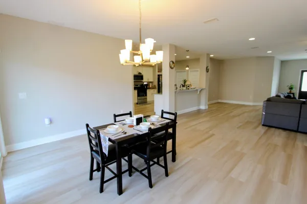 a view of a dining room with furniture a chandelier and wooden floor
