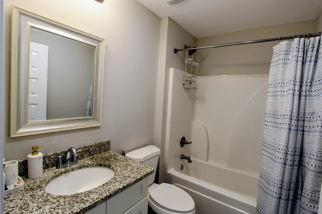 a bathroom with a granite countertop sink toilet and shower