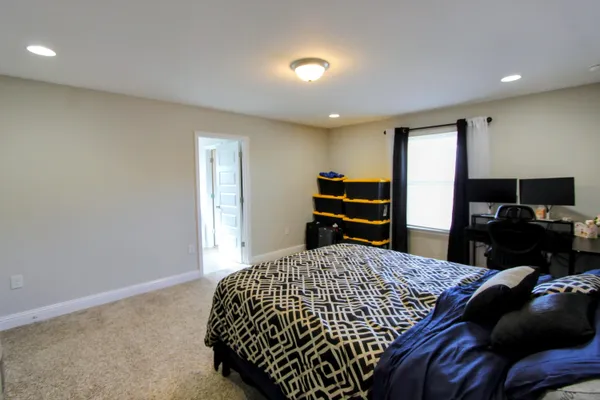 a bedroom with a bed and dresser with mirror