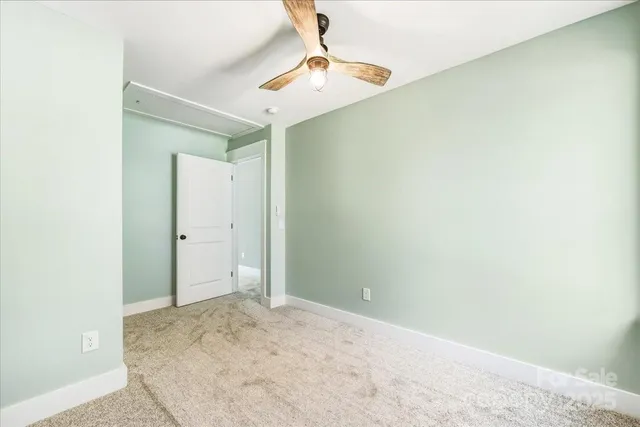 an empty room with a ceiling fan and carpet