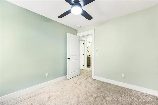 an empty room with a ceiling fan and carpet