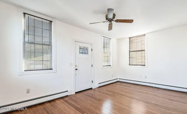 a view of empty room with wooden floor and fan