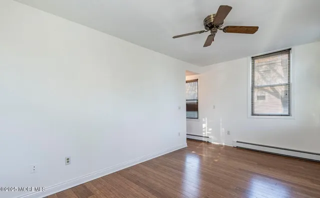 an empty room with wooden floor and a ceiling fan