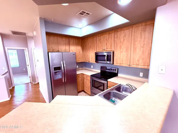 a kitchen with stainless steel appliances kitchen island granite countertop a refrigerator and a sink