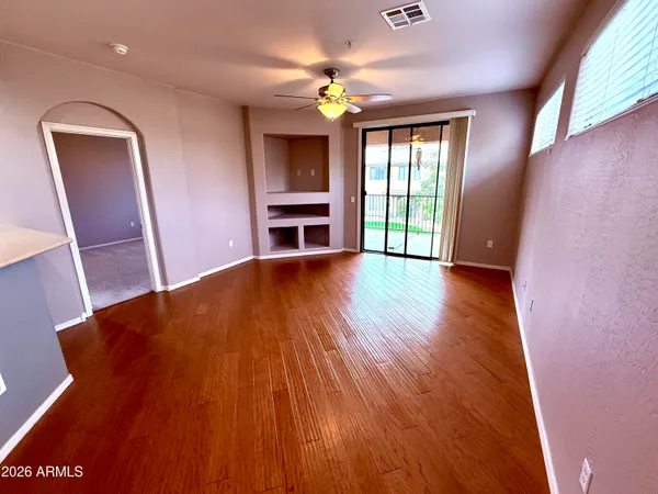 a view of an empty room with a window and wooden floor