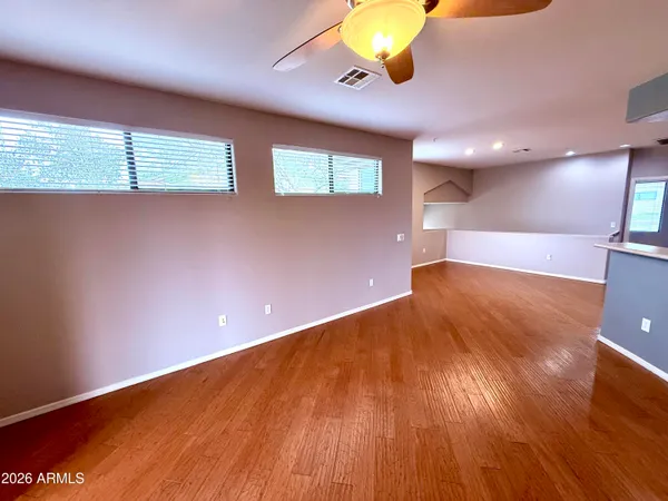 a view of an empty room with a window and wooden floor