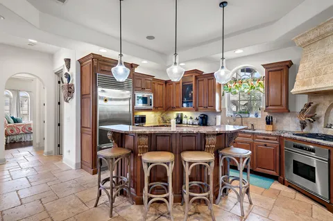 a kitchen with granite countertop wooden cabinets a dining table and chairs
