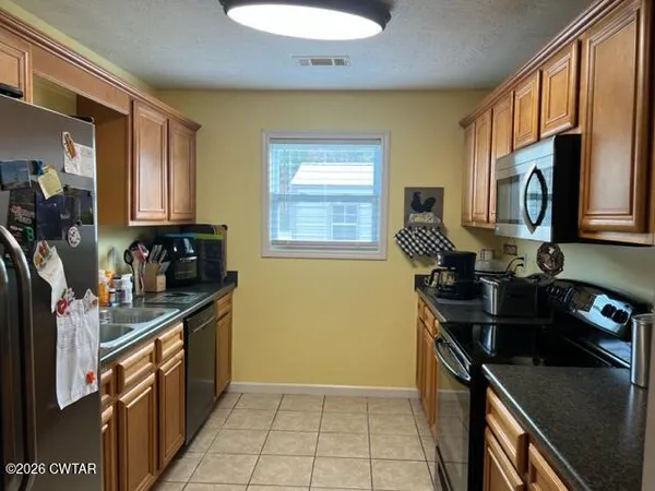 a kitchen with a sink appliances cabinets and a window