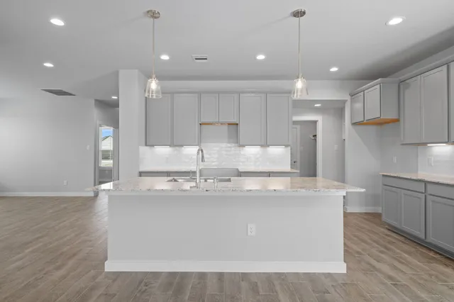 a large kitchen with kitchen island a stove a sink a center island and wooden floor