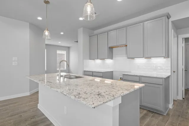 a kitchen with kitchen island granite countertop a sink and refrigerator
