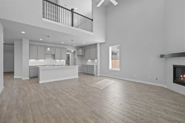 an empty room with wooden floor fireplace and windows