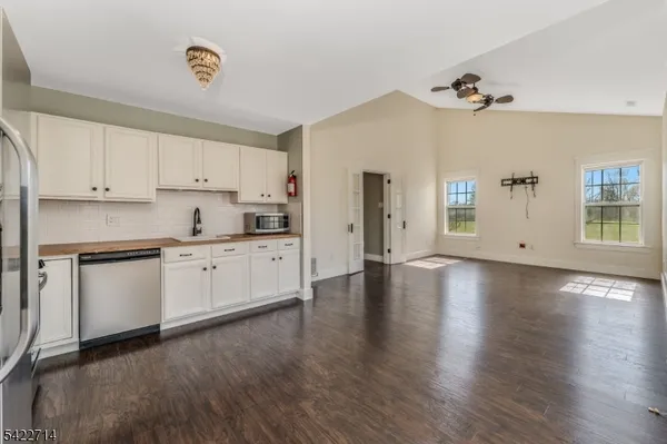 a kitchen with granite countertop a stove a sink white cabinets and wooden floor