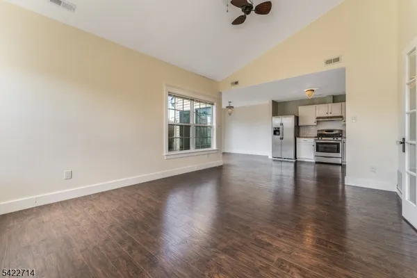 an empty room with wooden floor bathroom view and windows