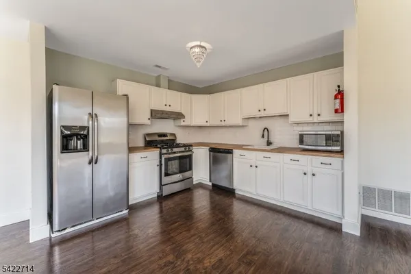 a kitchen with granite countertop white cabinets and stainless steel appliances