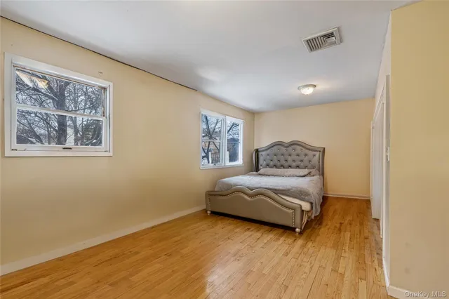 a spacious bedroom with a bed and wooden floor