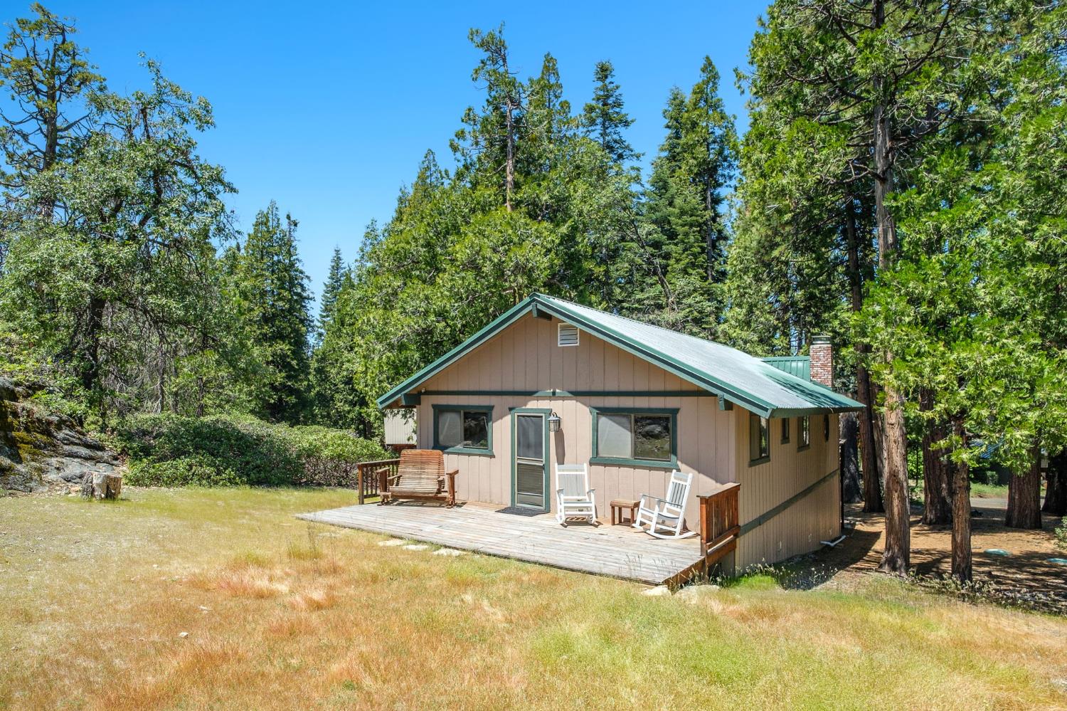 42488 Rock Ledge Road Shaver Lake, CA 93664 - Photo 1 of 26 a front view of a house with a yard table and chairs