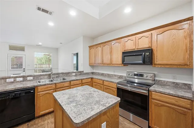 a kitchen with stainless steel appliances granite countertop a stove a sink and a microwave